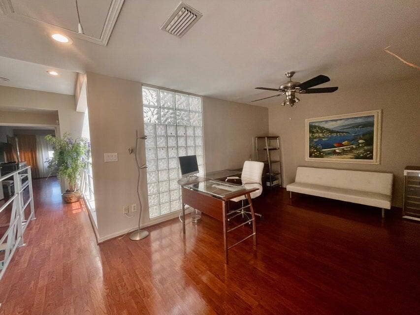 1127 BOCA COVE Lane, Highland Beach, FL 33487 Rich wood-finish flooring, glass block wall, ceiling fan, recessed lighting, and white railing