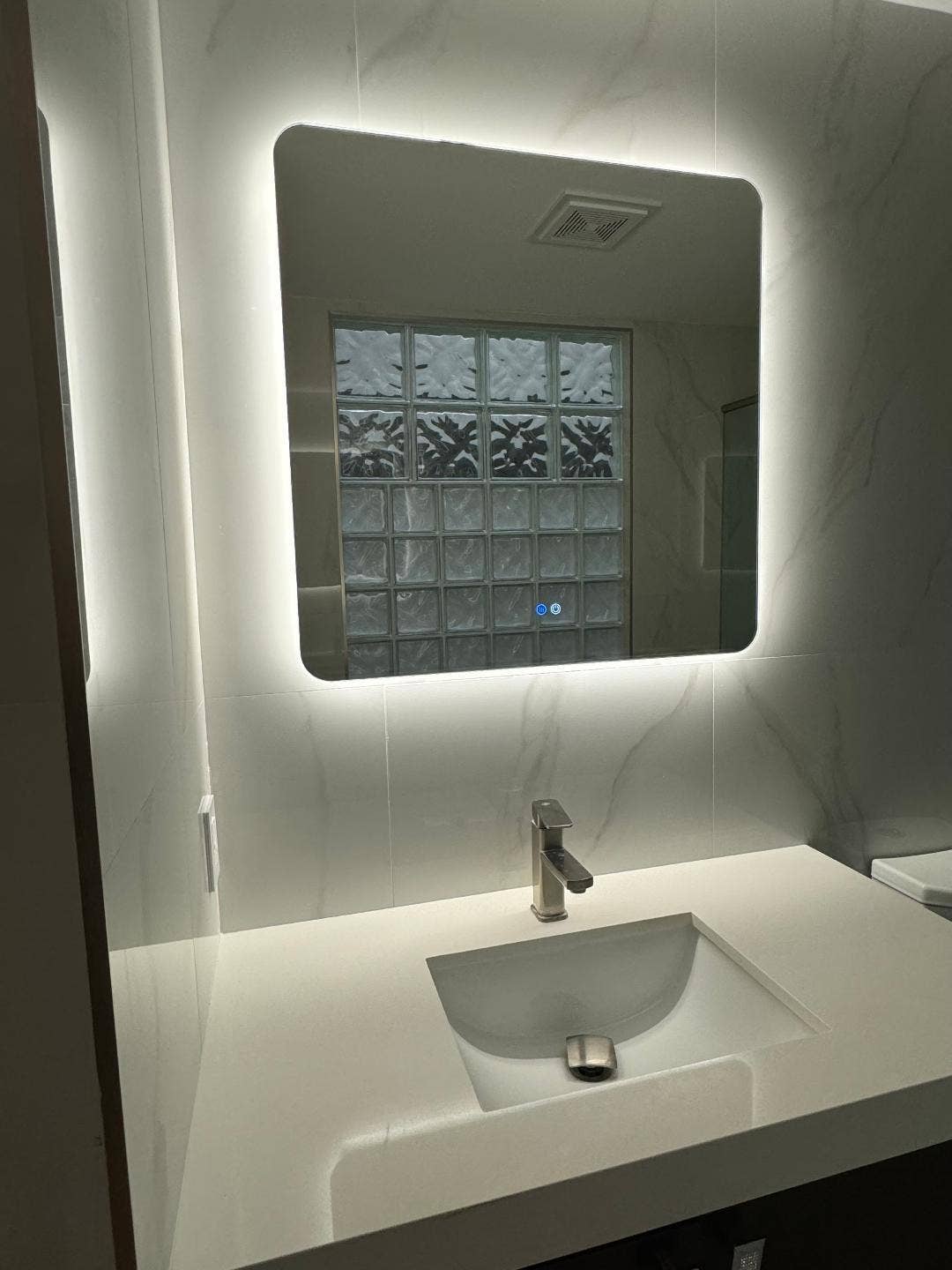 1127 BOCA COVE Lane, Highland Beach, FL 33487 Backlit mirror, integrated sink, brushed nickel faucet, large format tile, and glass block window