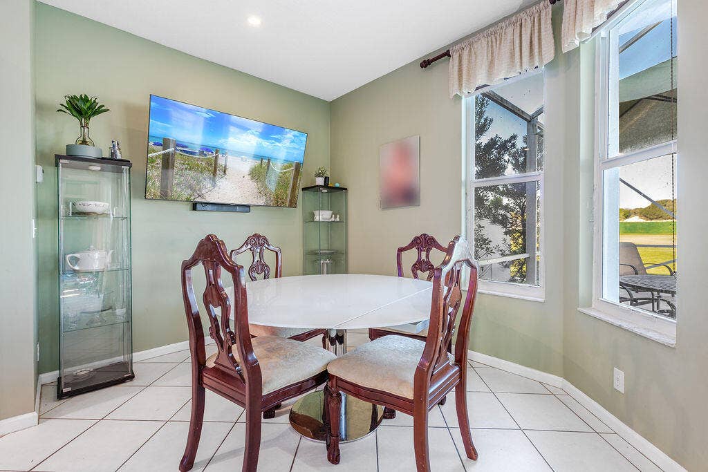 1233 Avondale Lane, West Palm Beach, FL 33409 Light-filled room featuring large windows, ceramic tile flooring, and wall-mounted television