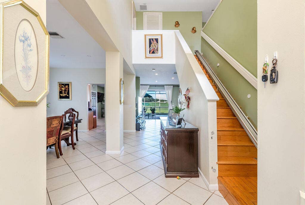 1233 Avondale Lane, West Palm Beach, FL 33409 Foyer featuring high ceilings, tile flooring, and a staircase with wood treads and a handrail
