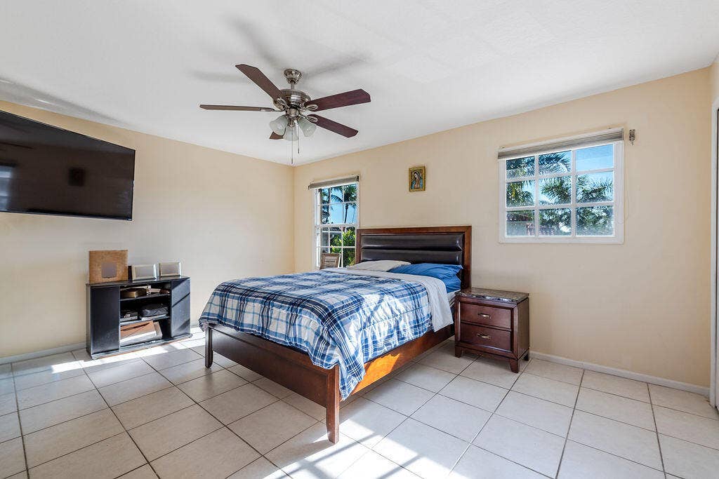 1233 Avondale Lane, West Palm Beach, FL 33409 Room featuring light-colored tile flooring, multiple windows with grid detailing, and a ceiling fan with integrated lighting