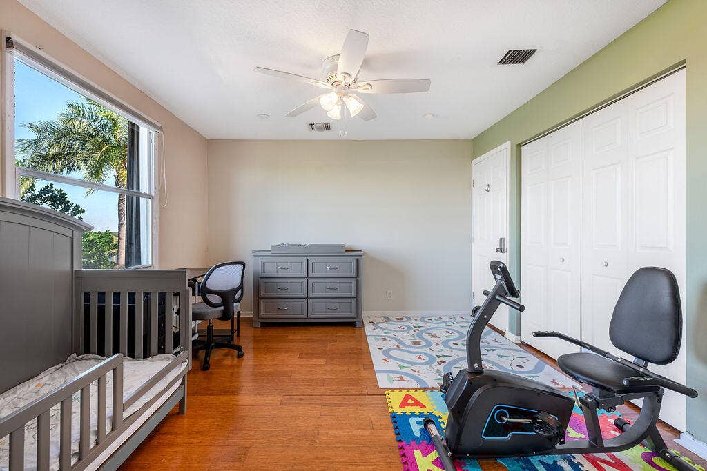 1233 Avondale Lane, West Palm Beach, FL 33409 Room featuring wood-finish flooring, a ceiling fan with integrated lighting, a large window, and double-door closet storage