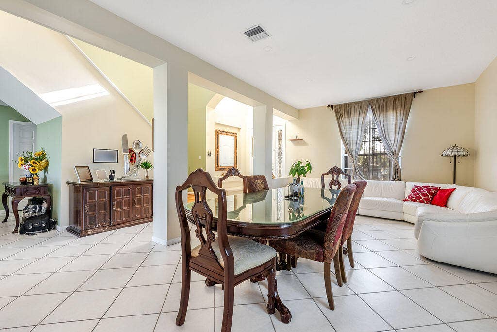 1233 Avondale Lane, West Palm Beach, FL 33409 Open-concept floor plan featuring ceramic tile flooring, recessed lighting, expansive archways, and a large window with custom drapery