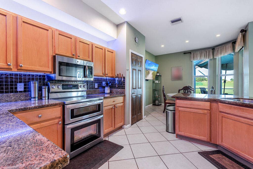 1233 Avondale Lane, West Palm Beach, FL 33409 Kitchen featuring natural-finish cabinetry, stone-finish countertops, dark tile backsplash, stainless steel double oven, and recessed lighting