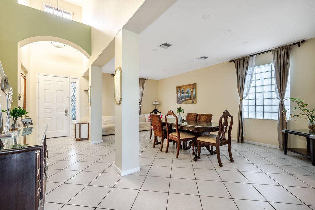 1233 Avondale Lane, West Palm Beach, FL 33409 Vaulted ceilings, expansive open-concept interior, arched architectural detailing, tile flooring, and glass block window feature
