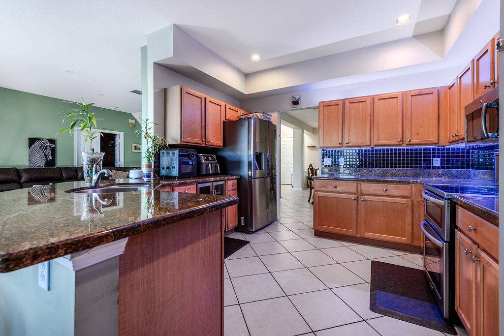 1233 Avondale Lane, West Palm Beach, FL 33409 Kitchen featuring wooden cabinetry, stone-surface countertops, tile flooring, a tile backsplash, and recessed lighting