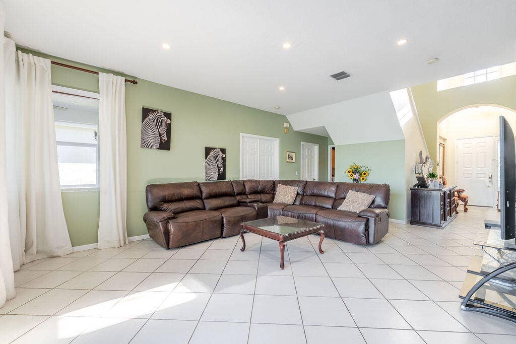1233 Avondale Lane, West Palm Beach, FL 33409 Open-concept interior featuring oversized ceramic tile flooring, recessed lighting, vaulted ceilings, and an arched entryway