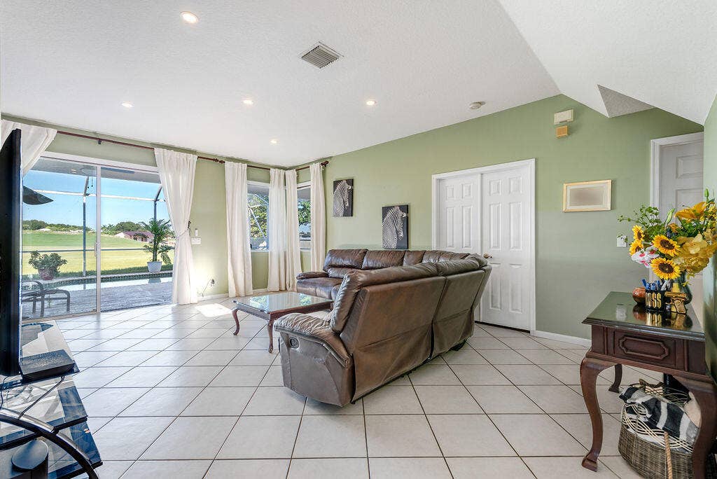 1233 Avondale Lane, West Palm Beach, FL 33409 Living area featuring high ceilings with recessed lighting, large ceramic tile flooring, and oversized glass sliding doors
