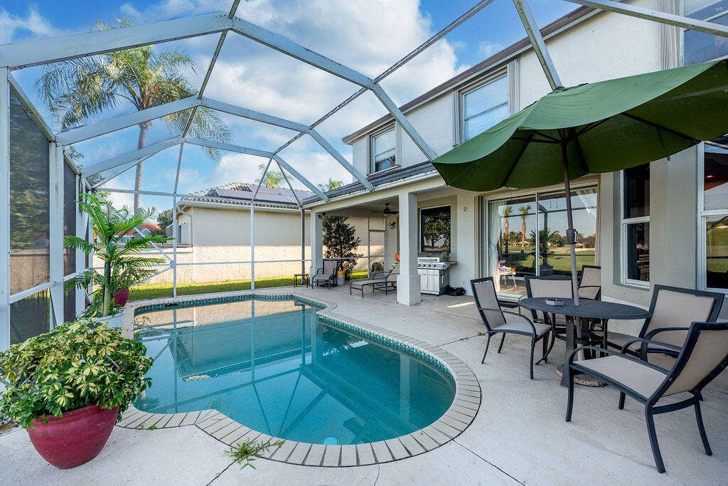 1233 Avondale Lane, West Palm Beach, FL 33409 Screen-enclosed patio featuring a swimming pool, concrete decking, and sliding glass door entry