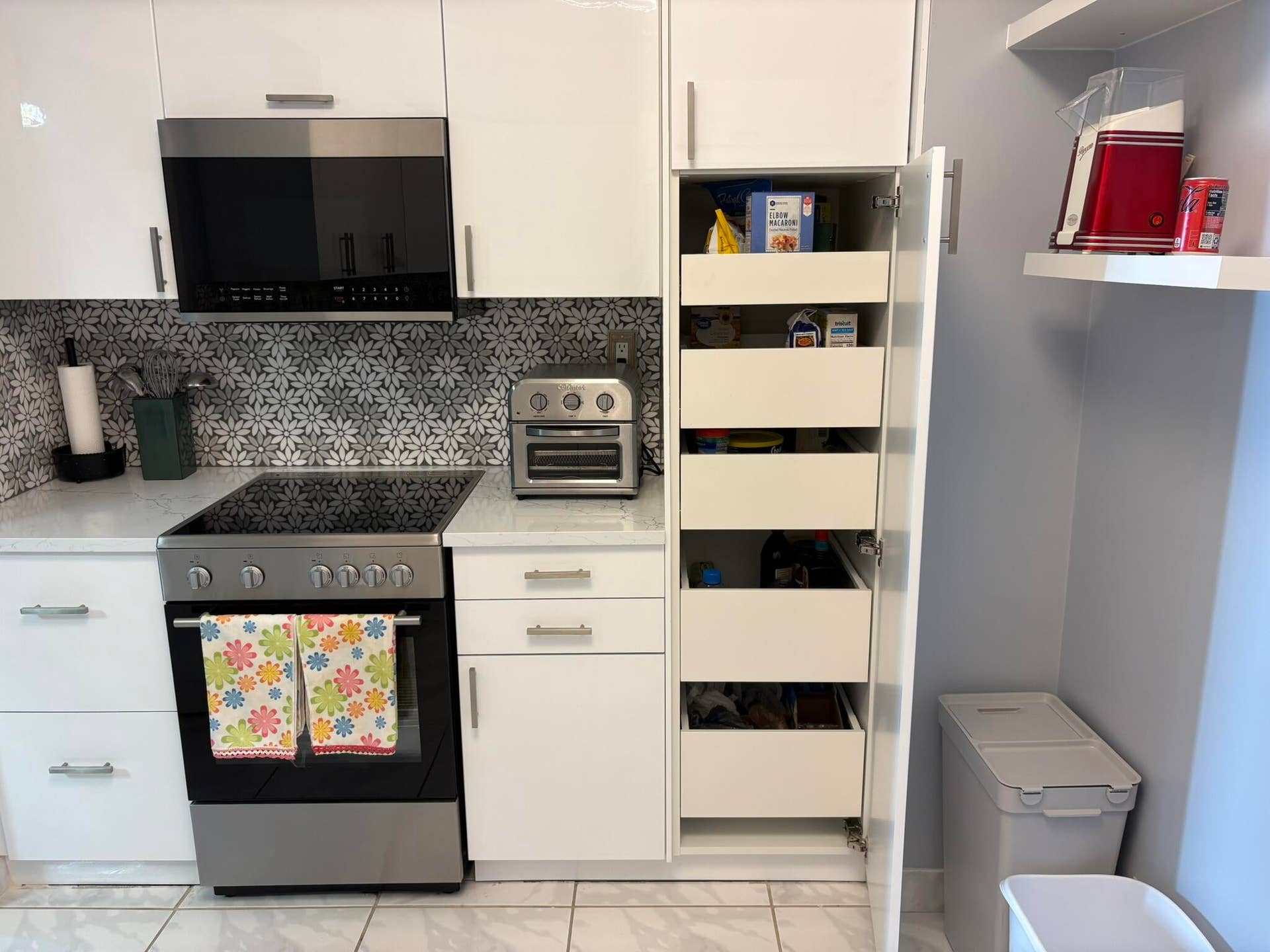 Kitchen featuring white high-gloss cabinetry, pull-out pantry shelving, a stainless steel electric range, a built-in microwave, and patterned tile backsplash
