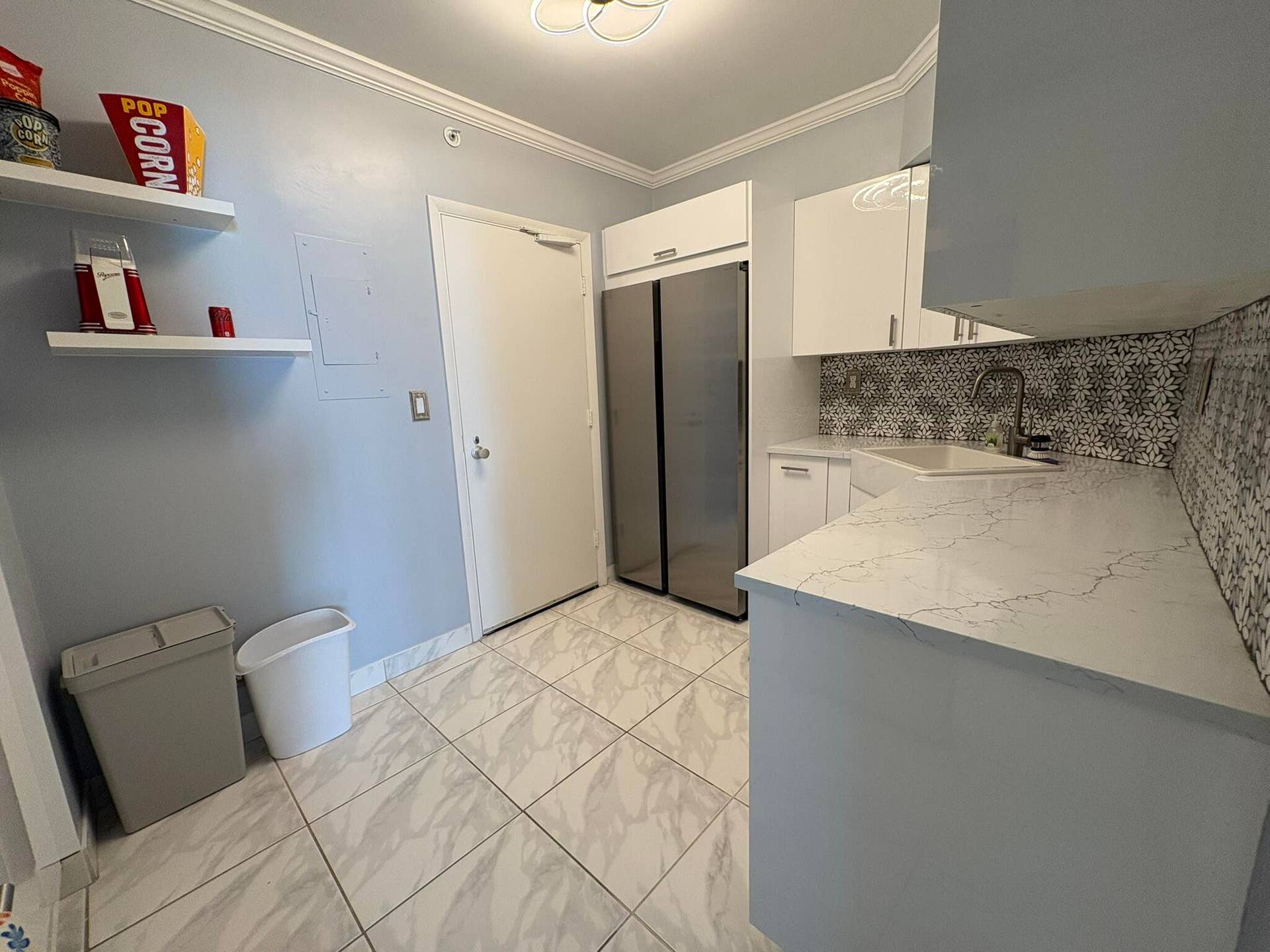 Kitchen featuring quartz countertops, white cabinetry, stainless steel side-by-side refrigerator, patterned tile backsplash, and stone-finish floor tiling