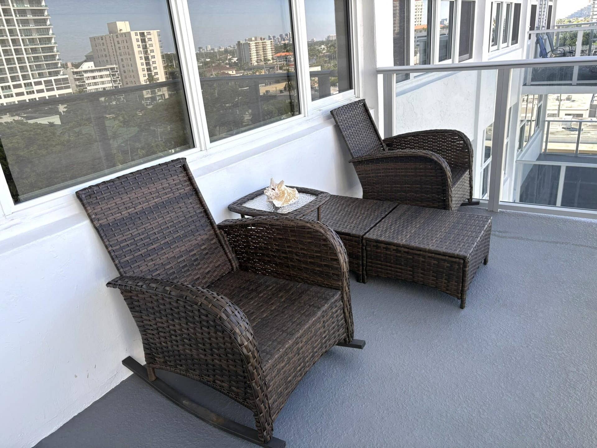Private balcony with painted concrete flooring, large window panels, and white metal railing