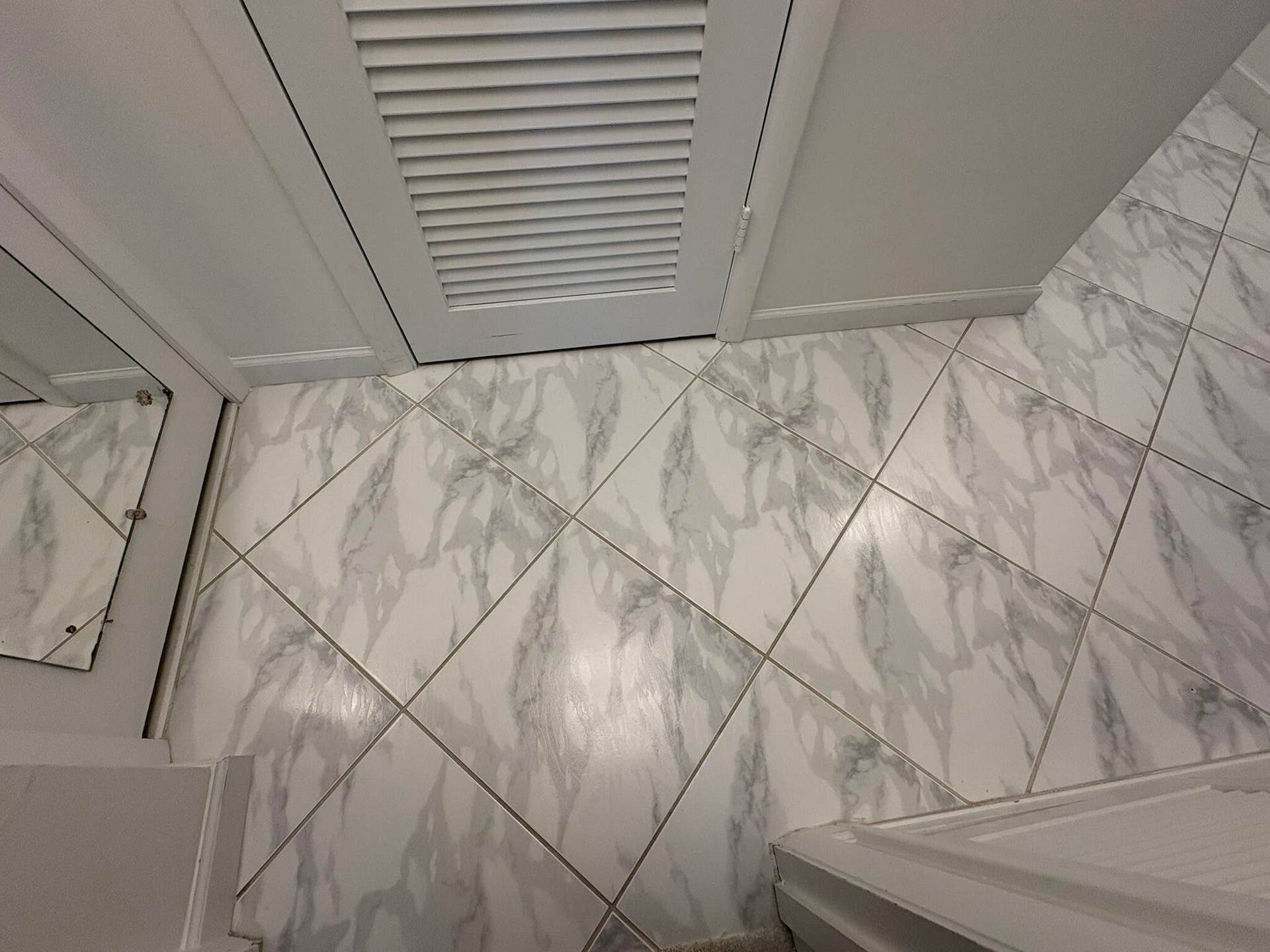 Diagonal-patterned tile flooring with stone-finish veining and louvered-panel cabinetry