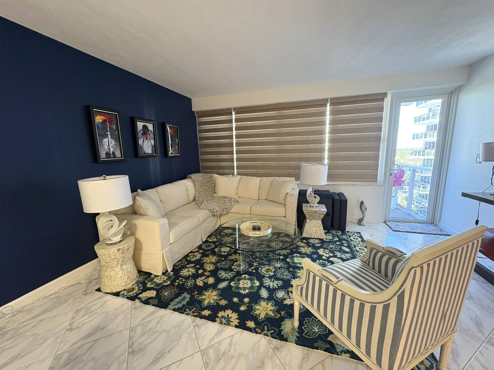Living area featuring large-format diagonal tile flooring, a prominent accent wall, and horizontal window shades