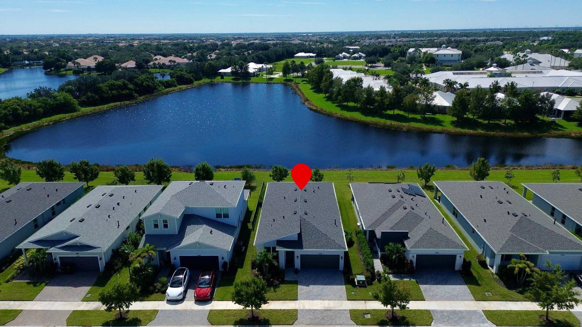 12688 SW Eleanor Drive, Port St Lucie, FL 34987 Aerial perspective of a residential community featuring multi-story dwellings, shingle roof architecture, paved driveways, and expansive waterfront positioning