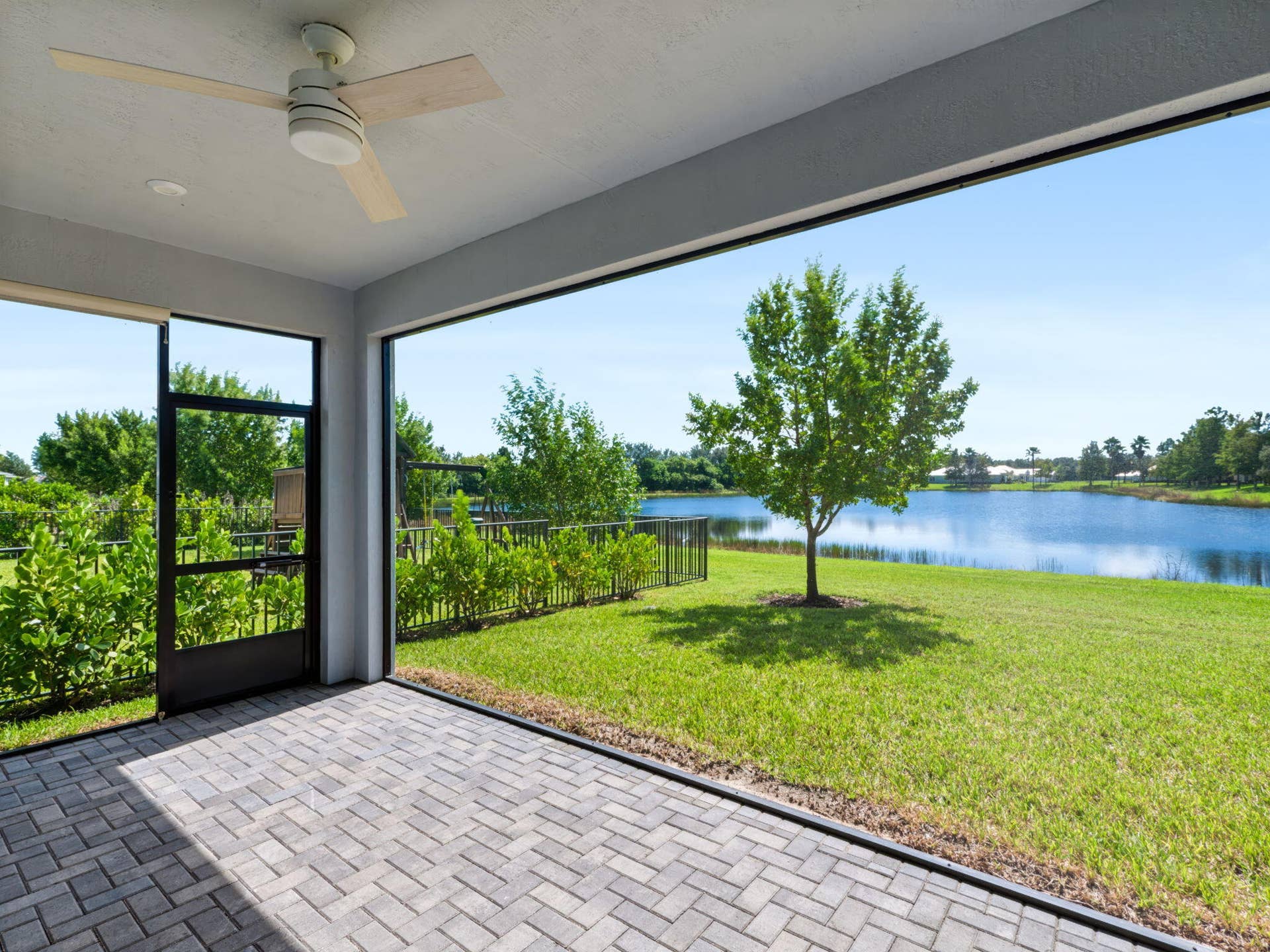 12688 SW Eleanor Drive, Port St Lucie, FL 34987 Covered screened-in patio featuring paver flooring, a ceiling fan, and lake frontage