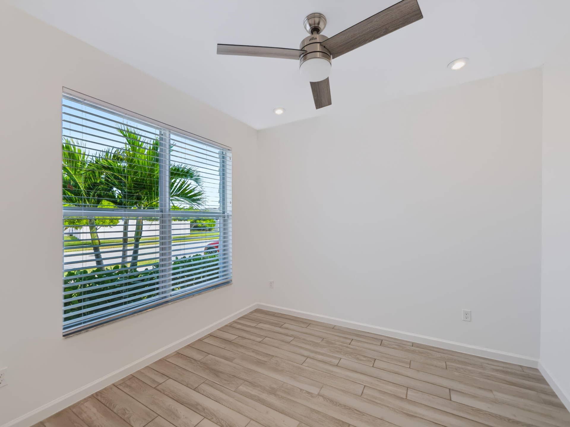 12688 SW Eleanor Drive, Port St Lucie, FL 34987 Neutral-toned interior featuring wood-finish flooring, a contemporary brushed-nickel ceiling fan, recessed lighting, and a window with horizontal blinds