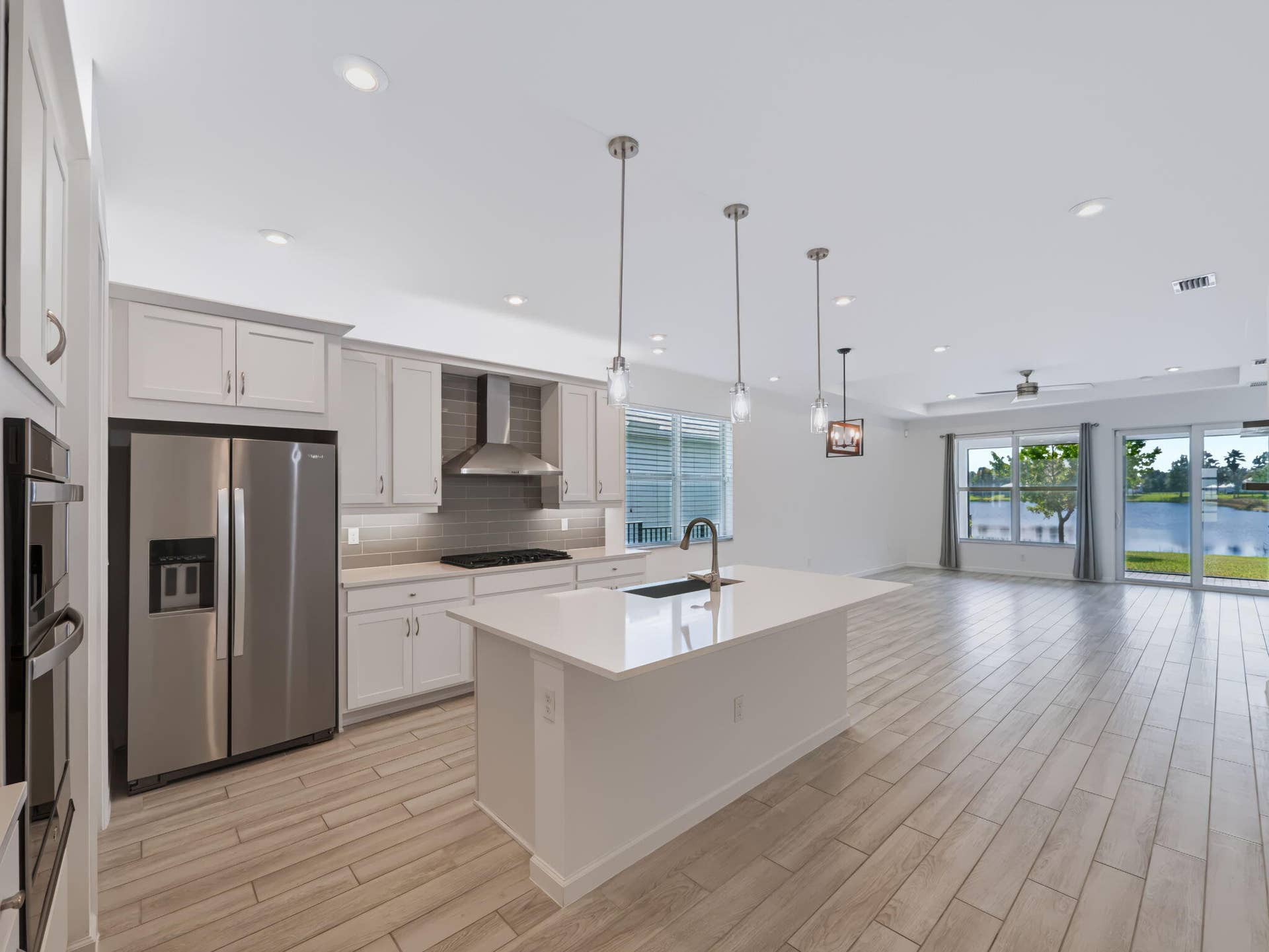 12688 SW Eleanor Drive, Port St Lucie, FL 34987 Kitchen featuring light-toned cabinetry, quartz countertops, stainless steel appliances, pendant lighting, and wood-finish flooring