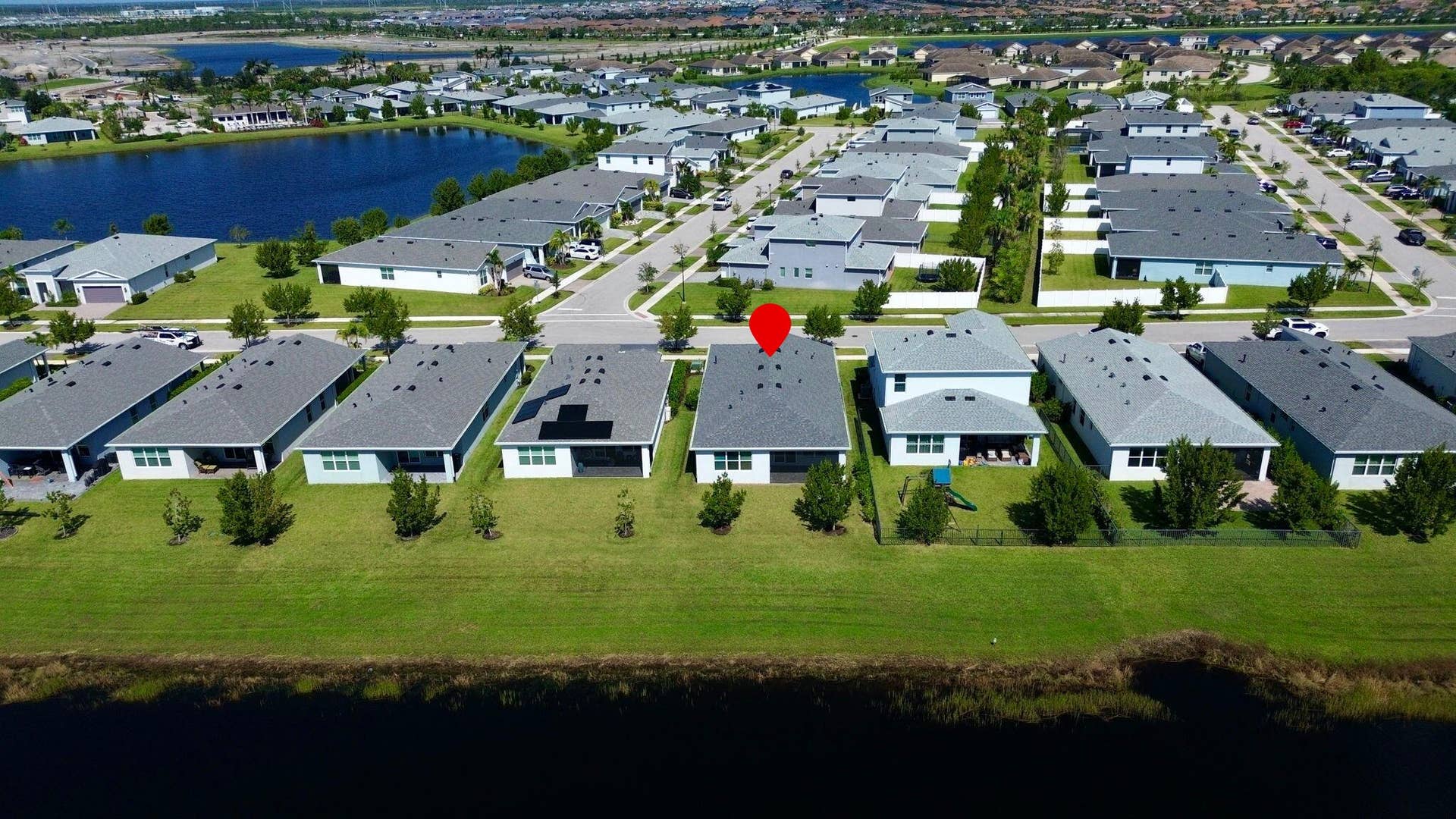 12688 SW Eleanor Drive, Port St Lucie, FL 34987 Aerial perspective of a residential community featuring multi-story dwellings, shingle roof architecture, paved driveways, and expansive waterfront positioning