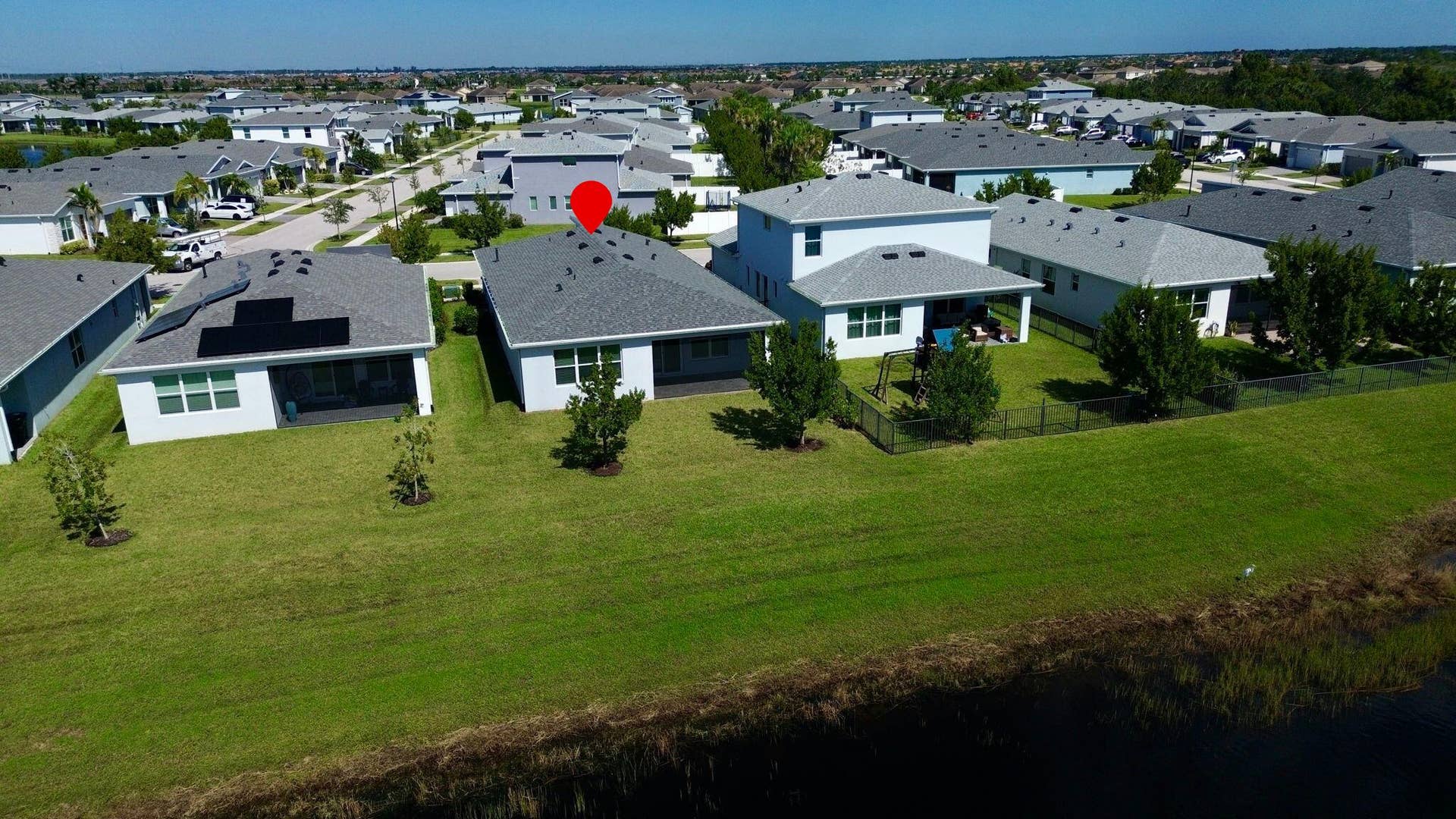 12688 SW Eleanor Drive, Port St Lucie, FL 34987 Aerial perspective of a residential community featuring multi-story dwellings, shingle roof architecture, paved driveways, and expansive waterfront positioning