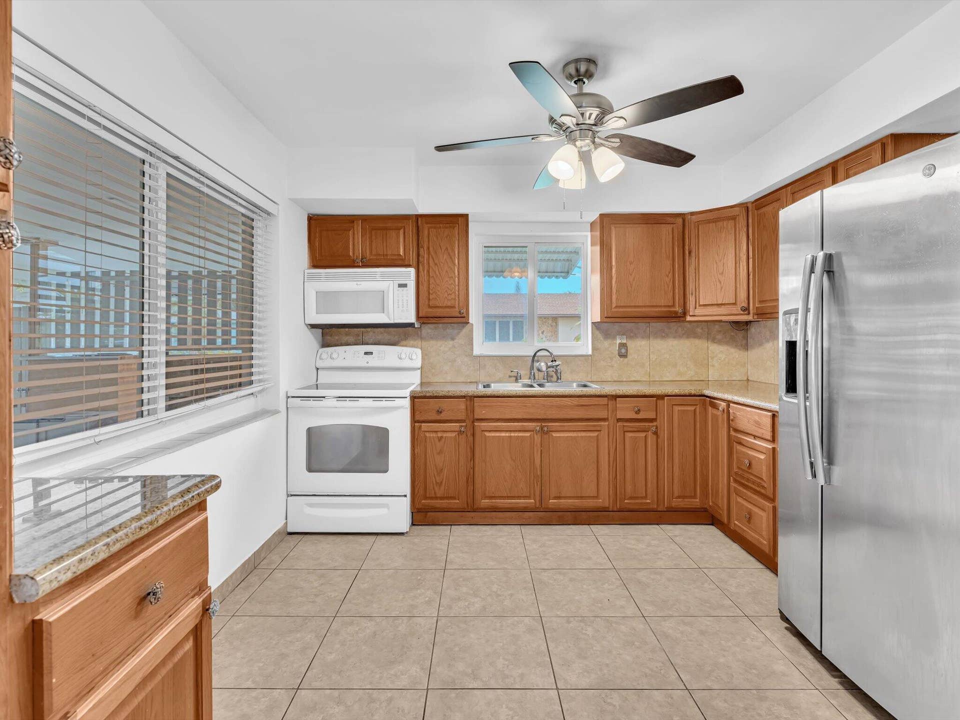 132 SE 2ND Court, Dania Beach, Dania Beach, FL 33004 Kitchen featuring stained wood cabinetry, stone-surface countertops, tile flooring, stainless steel refrigerator, and ceiling fan with integrated lighting