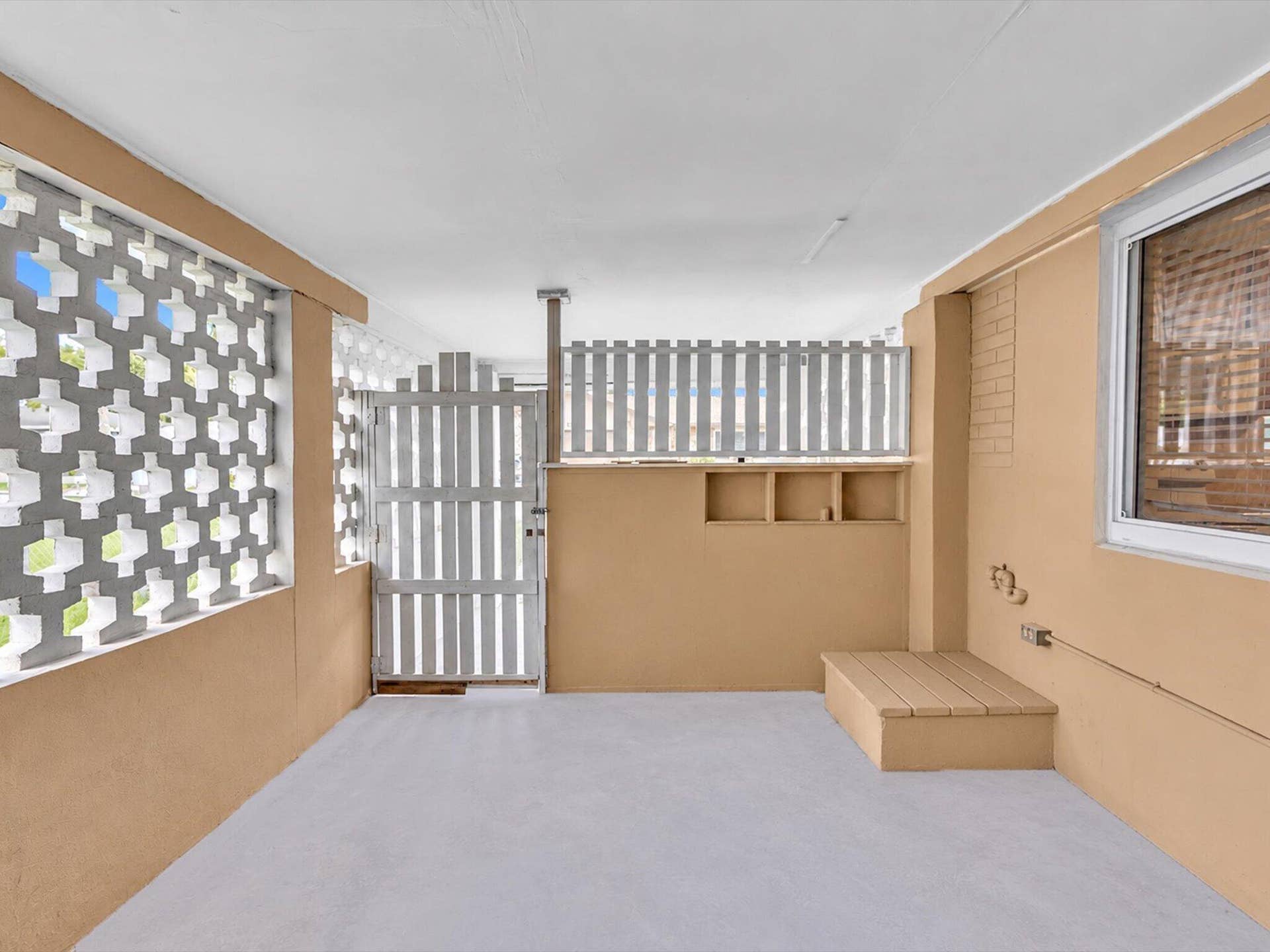 132 SE 2ND Court, Dania Beach, Dania Beach, FL 33004 Covered outdoor area featuring geometric concrete breeze block walling, a wood-finish platform, built-in shelving, and a vertical-slat privacy gate