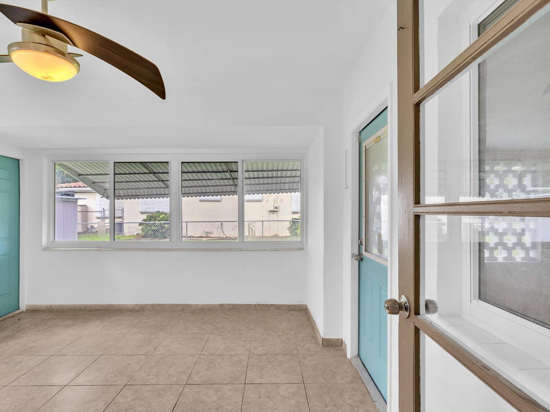 132 SE 2ND Court, Dania Beach, Dania Beach, FL 33004 Enclosed porch featuring ceramic tile flooring, large-pane windows, a ceiling fan with integrated lighting, and a multi-lite door