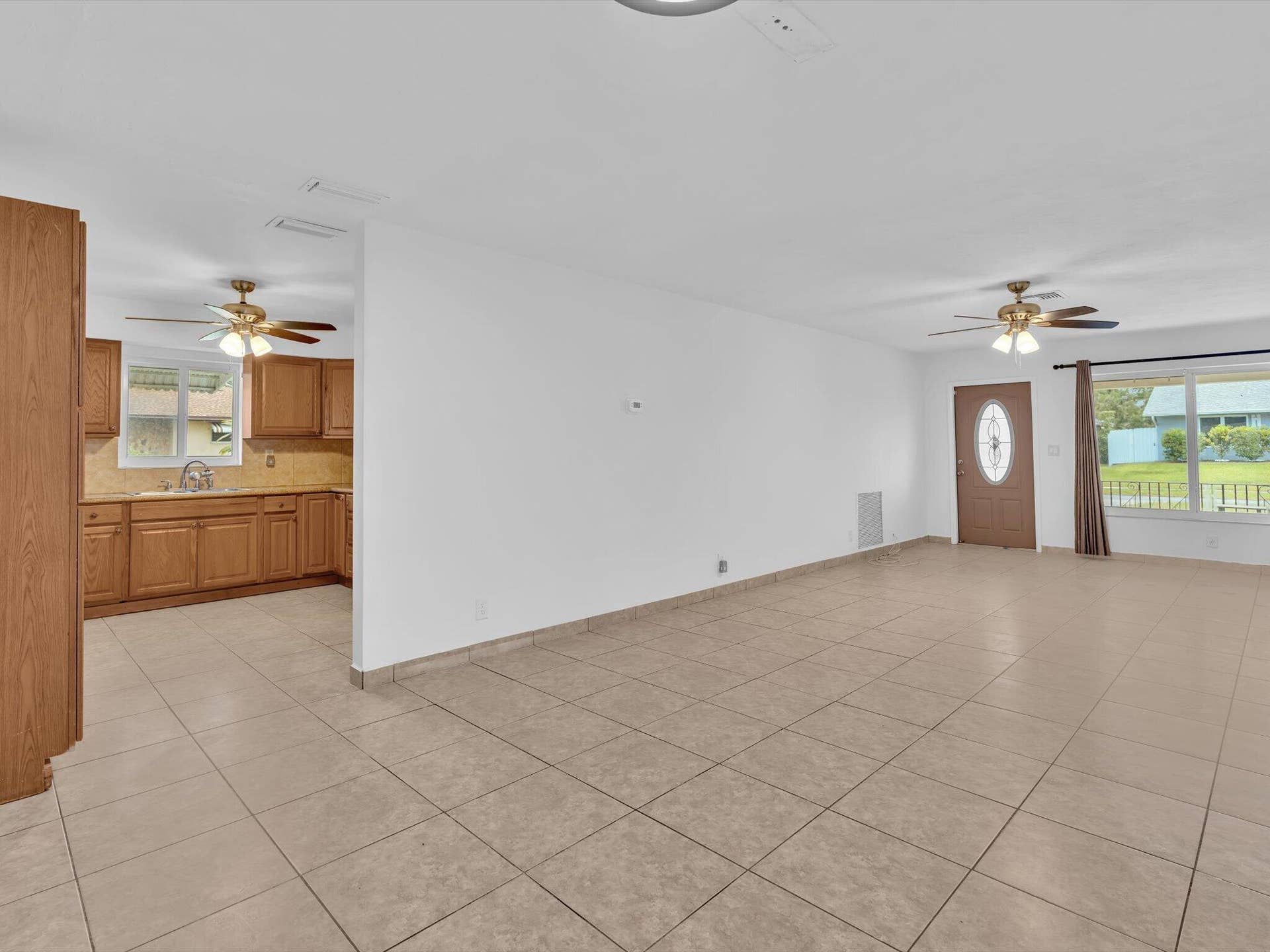 132 SE 2ND Court, Dania Beach, Dania Beach, FL 33004 Ceramic tile flooring, natural wood cabinetry, neutral interior paint, dual ceiling fans, and an exterior door with an oval glass insert