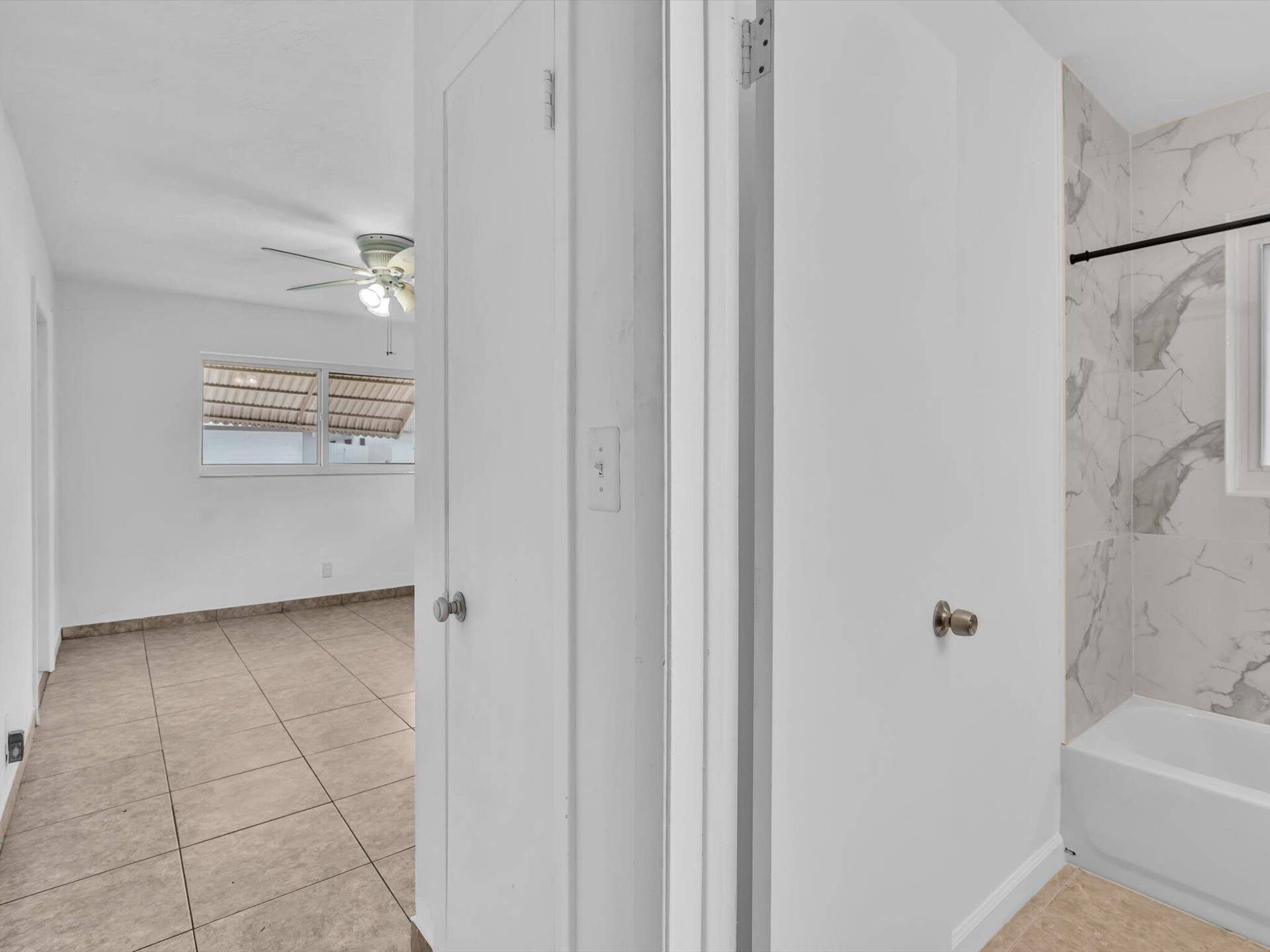 132 SE 2ND Court, Dania Beach, Dania Beach, FL 33004 Ceramic tile flooring, white interior doors, and a tiled shower surround with a built-in tub