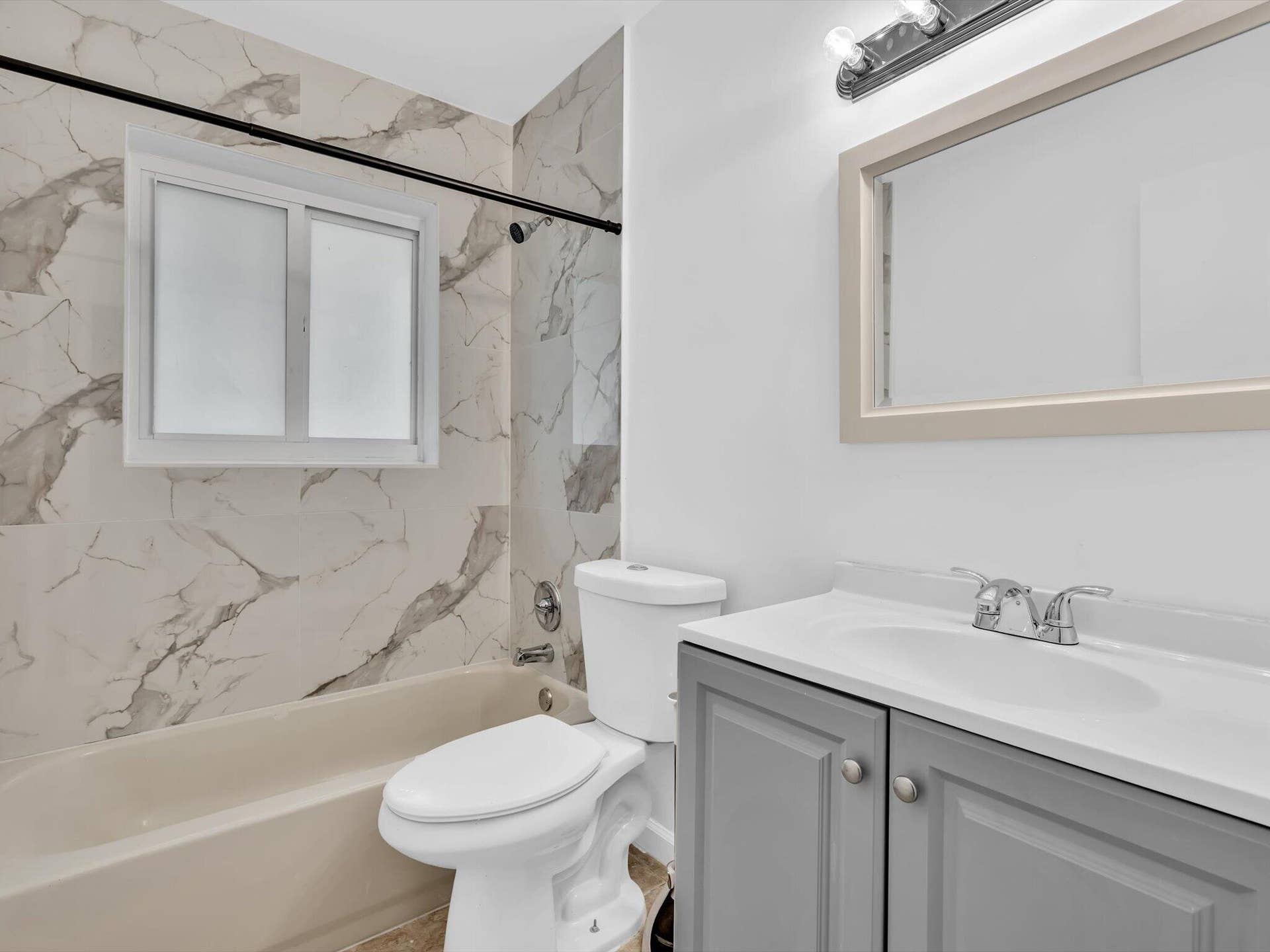 132 SE 2ND Court, Dania Beach, Dania Beach, FL 33004 Bathroom featuring a vanity with a white countertop, large-format tile shower surround, neutral bathtub, framed wall mirror, and chrome-finish hardware