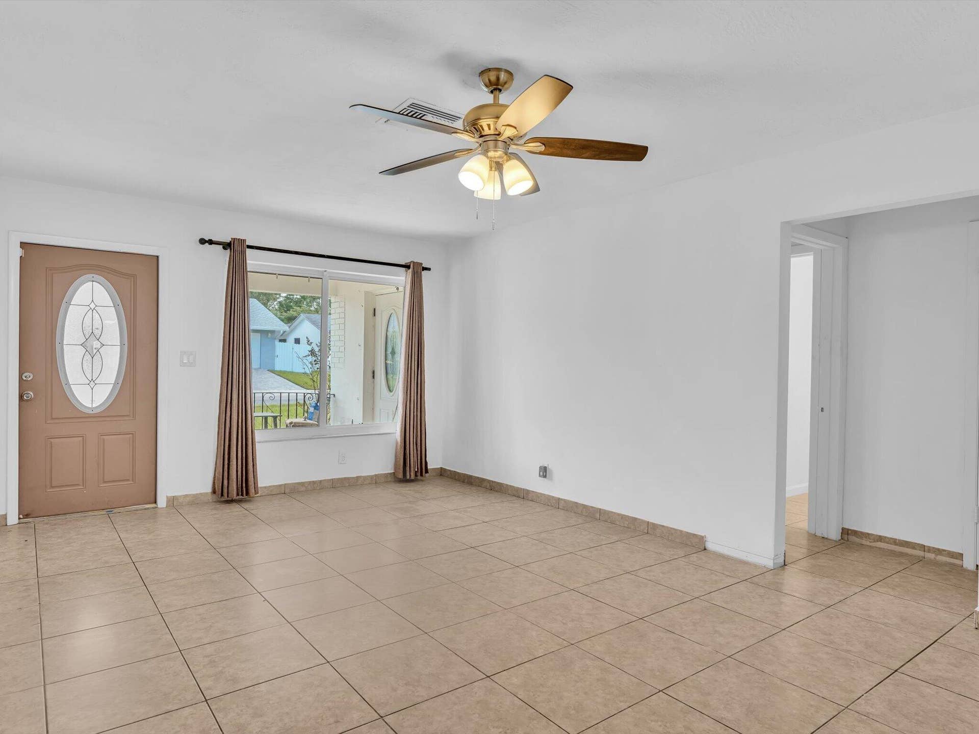 132 SE 2ND Court, Dania Beach, Dania Beach, FL 33004 Neutral tile flooring, exterior door with oval glass insert, multi-light ceiling fan, and large picture window