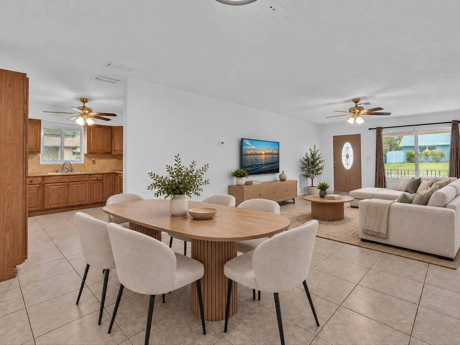 132 SE 2ND Court, Dania Beach, Dania Beach, FL 33004 Open-concept interior featuring light-colored tile flooring, wood cabinetry with stone-finish countertops, dual ceiling fans, and an entry door with an oval glass insert