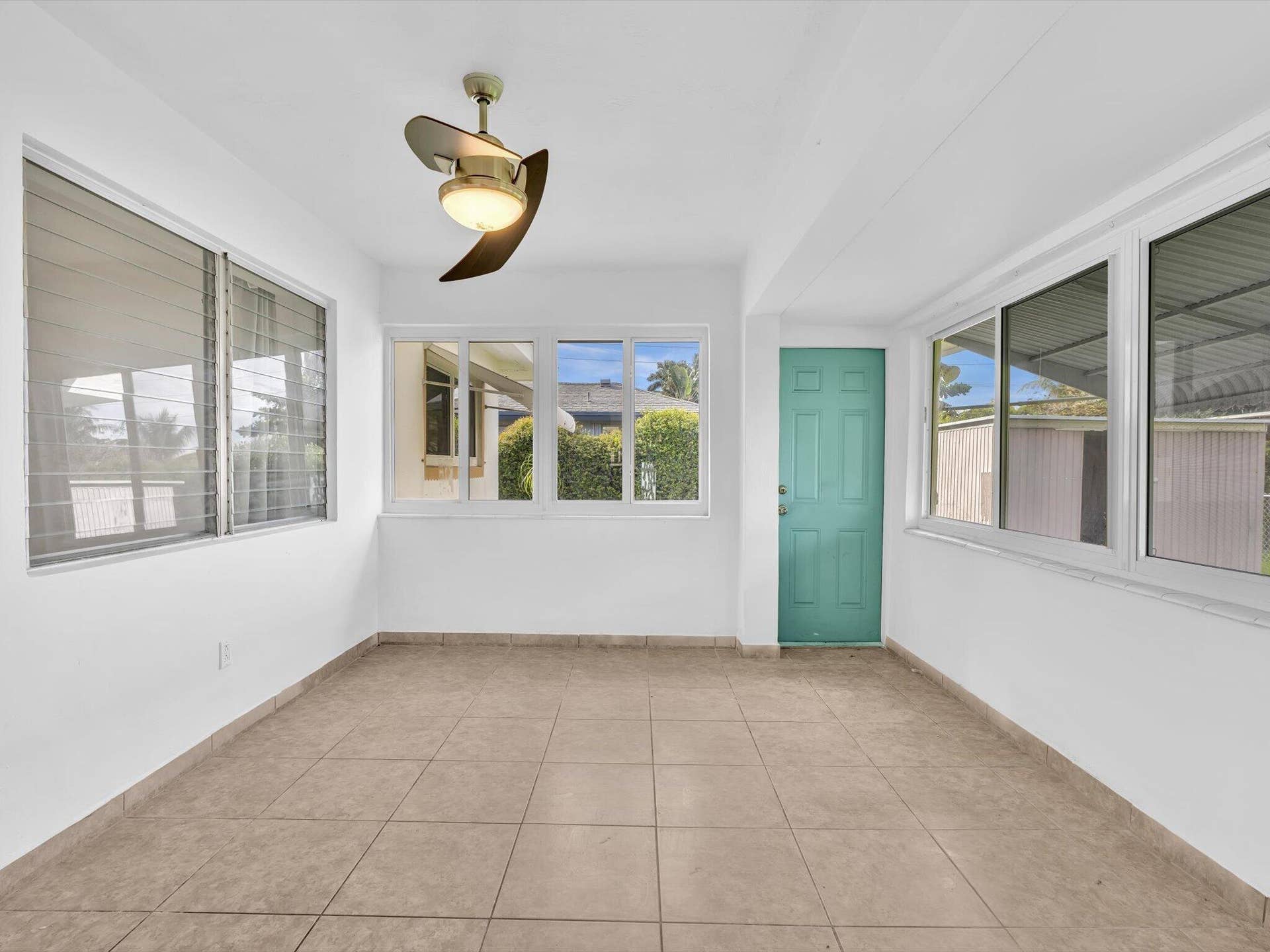 132 SE 2ND Court, Dania Beach, Dania Beach, FL 33004 Enclosed space featuring ceramic tile flooring, multiple large windows, a ceiling fan with integrated lighting, and a six-panel entry door