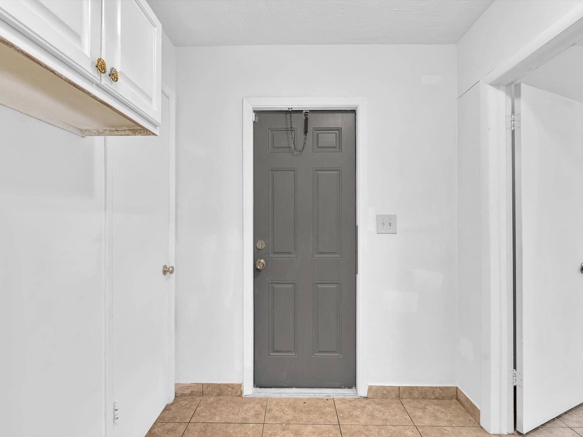 132 SE 2ND Court, Dania Beach, Dania Beach, FL 33004 Entry area featuring a six-panel gray door with metallic hardware, white cabinetry, and neutral tile flooring
