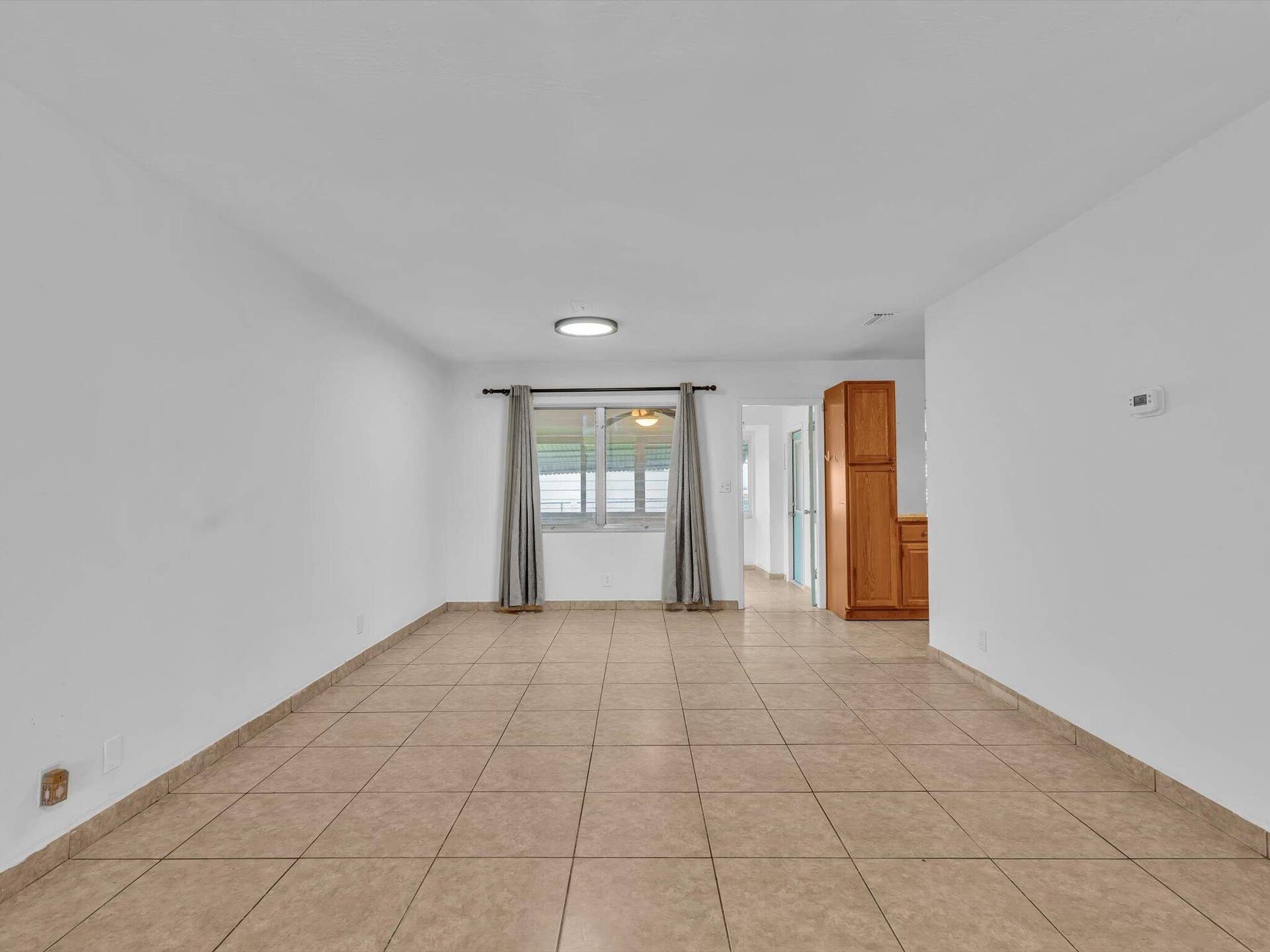 132 SE 2ND Court, Dania Beach, Dania Beach, FL 33004 Spacious room featuring neutral tile flooring, a large window, flush-mount lighting, and built-in wood cabinetry