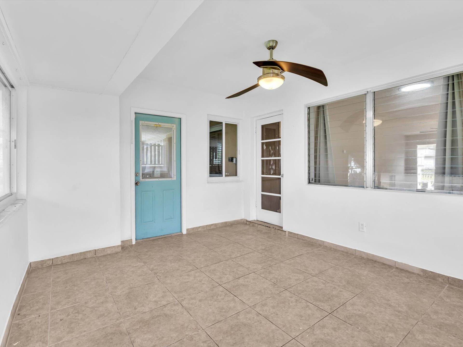 132 SE 2ND Court, Dania Beach, Dania Beach, FL 33004 Enclosed sunroom featuring ceramic tile flooring, a multi-pane glass entry door, jalousie windows, and an integrated ceiling fan with light fixture