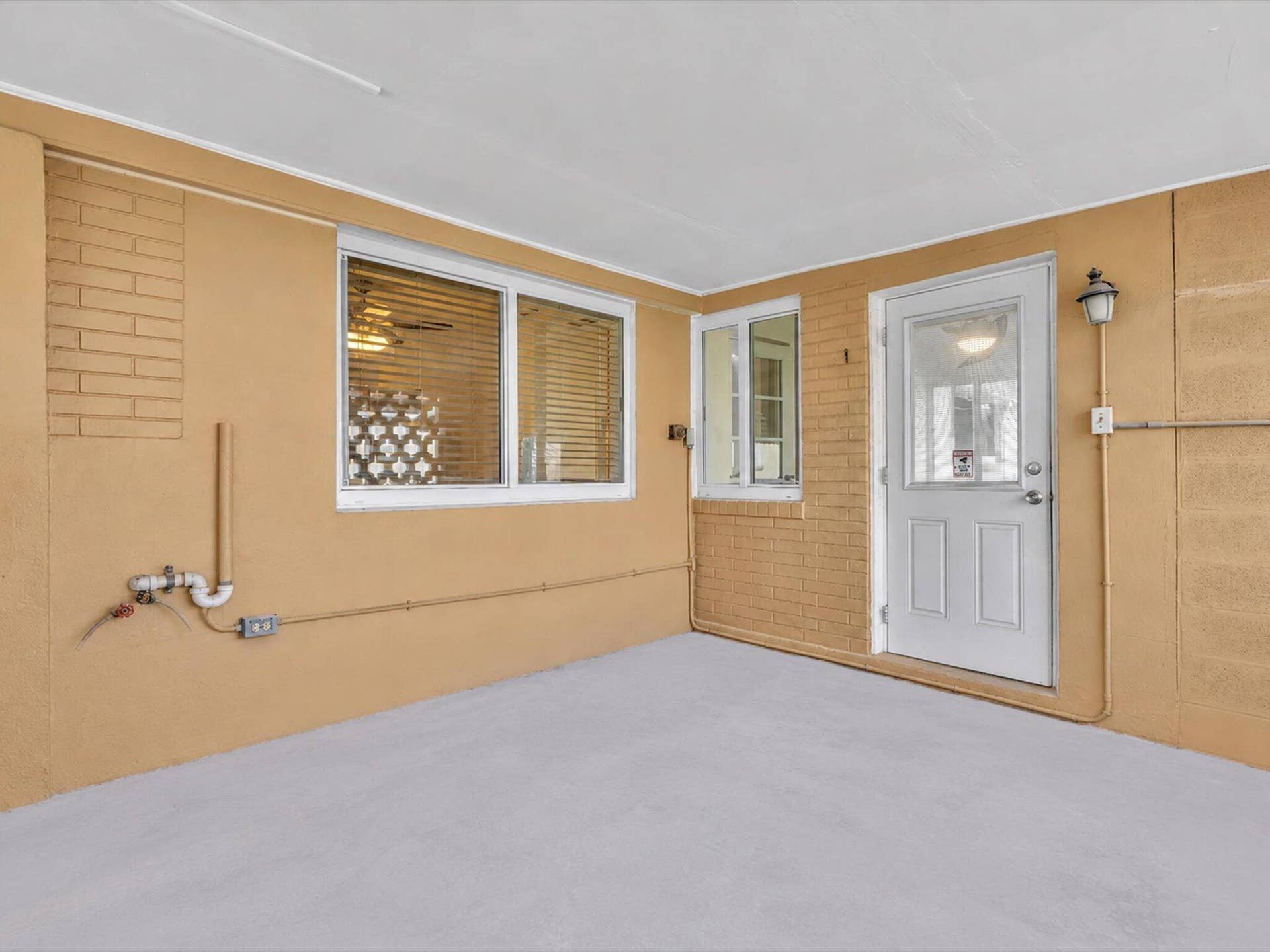 132 SE 2ND Court, Dania Beach, Dania Beach, FL 33004 Covered patio featuring tan painted brick masonry, concrete flooring, dual-pane windows, and a glass-inset entry door