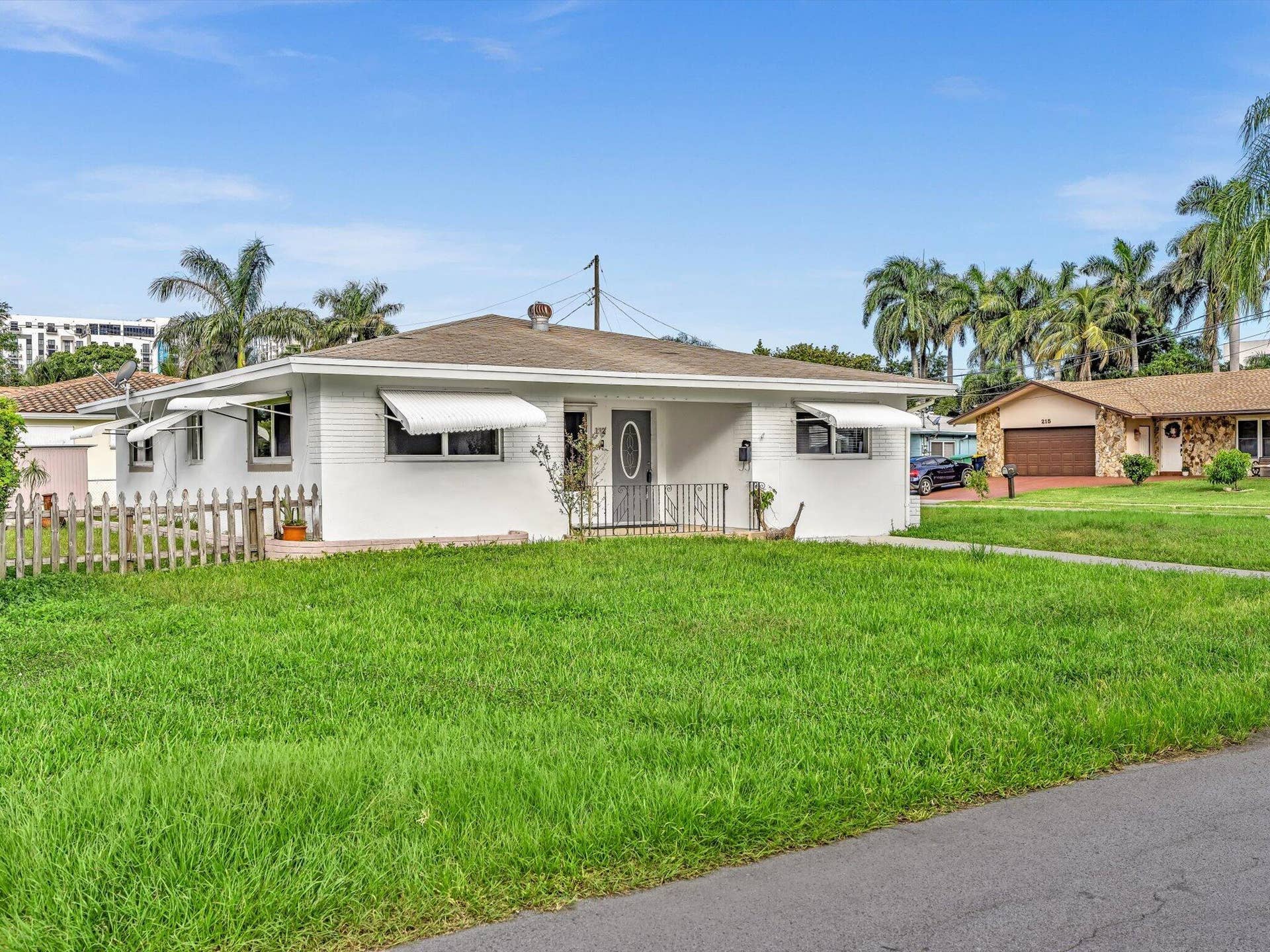 132 SE 2ND Court, Dania Beach, Dania Beach, FL 33004 White painted brick exterior featuring metal window awnings, a covered front entryway with iron railing, and a picket fence