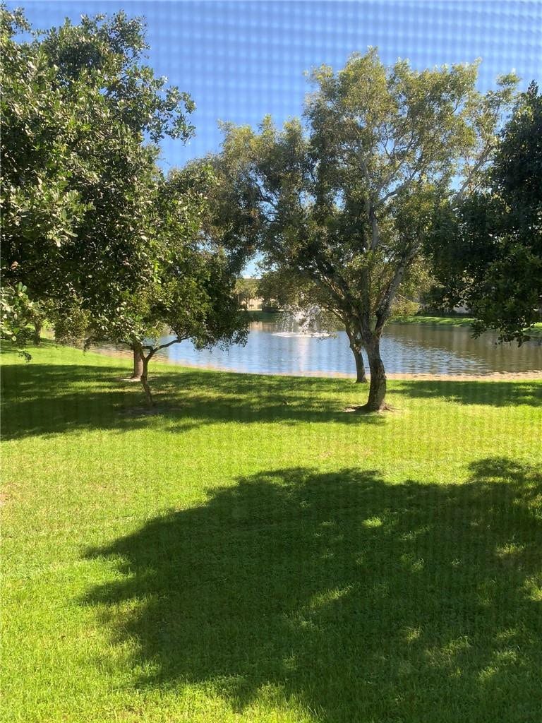 2305 LUCAYA Lane, #L4, Coconut Creek, Coconut Creek, FL 33066 Waterfront lot featuring a pond, fountain, and mature trees situated on a grass lawn