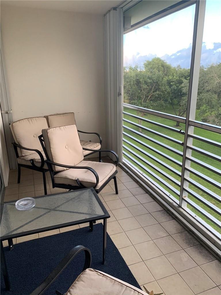 2305 LUCAYA Lane, #L4, Coconut Creek, Coconut Creek, FL 33066 Covered balcony featuring tile flooring, metal railings, floor-to-ceiling glass panels, and mountain scenery