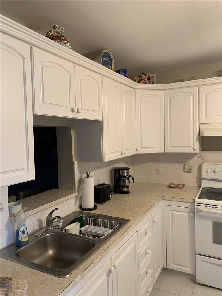 2305 LUCAYA Lane, #L4, Coconut Creek, Coconut Creek, FL 33066 Kitchen featuring white cabinetry, light-toned laminate countertops, a stainless steel double-basin sink, and a white free-standing range