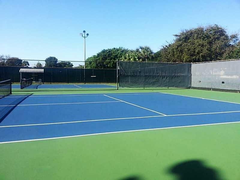 2305 LUCAYA Lane, #L4, Coconut Creek, Coconut Creek, FL 33066 Tennis court featuring a high-contrast two-tone surface, perimeter fencing, and integrated wind screens