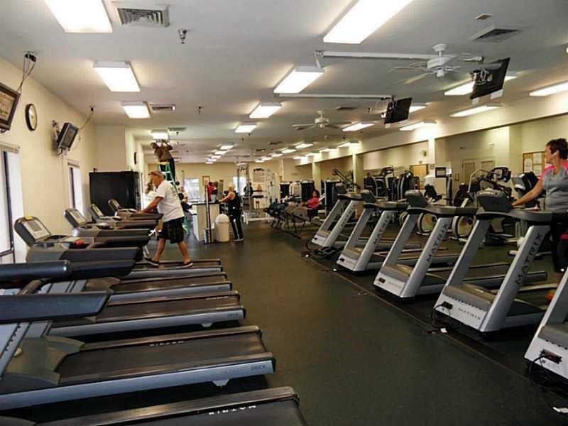 2305 LUCAYA Lane, #L4, Coconut Creek, Coconut Creek, FL 33066 Fitness center featuring rubber flooring, recessed fluorescent lighting, ceiling-mounted fans, wall-mounted televisions, and built-in exercise equipment