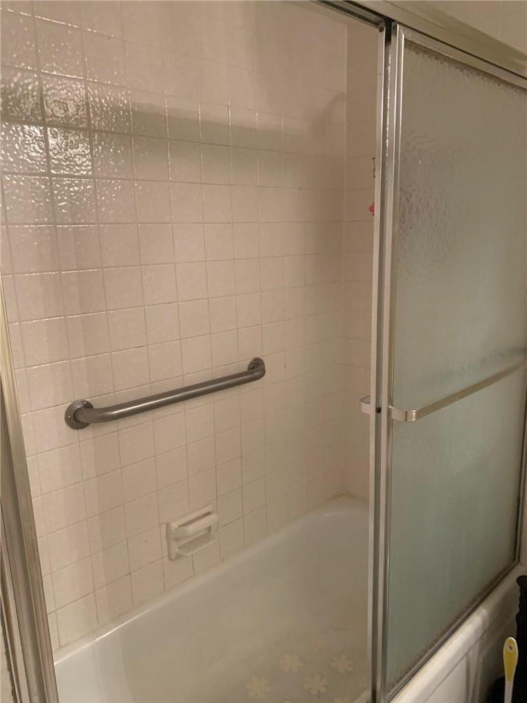 2305 LUCAYA Lane, #L4, Coconut Creek, Coconut Creek, FL 33066 Bathtub shower combination featuring square wall tiling, metal sliding enclosure, and integrated metal grab bar