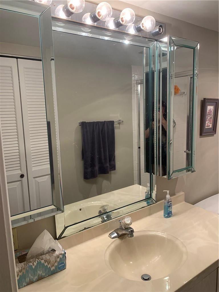 2305 LUCAYA Lane, #L4, Coconut Creek, Coconut Creek, FL 33066 Multi-paneled mirrored vanity cabinet with integrated lighting, polished countertop, and single-basin sink featuring a chrome faucet