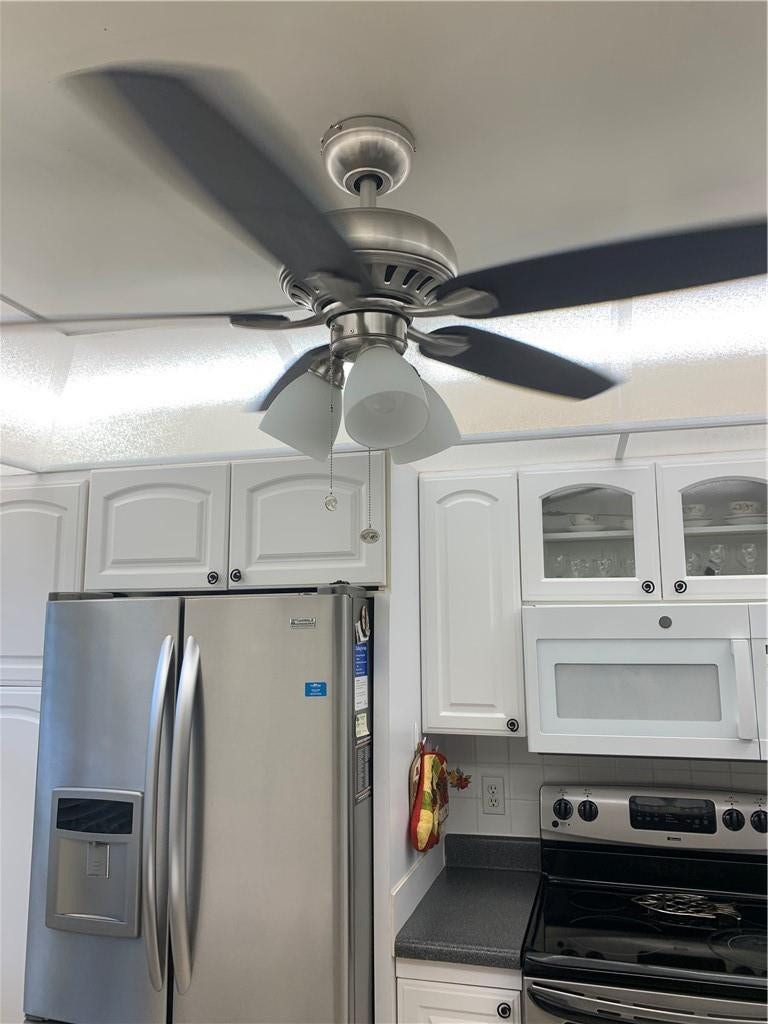2305 LUCAYA Lane, #L4, Coconut Creek, Coconut Creek, FL 33066 Brushed nickel ceiling fan with frosted glass shades, white cabinetry with glass-front accents, and stainless steel appliances
