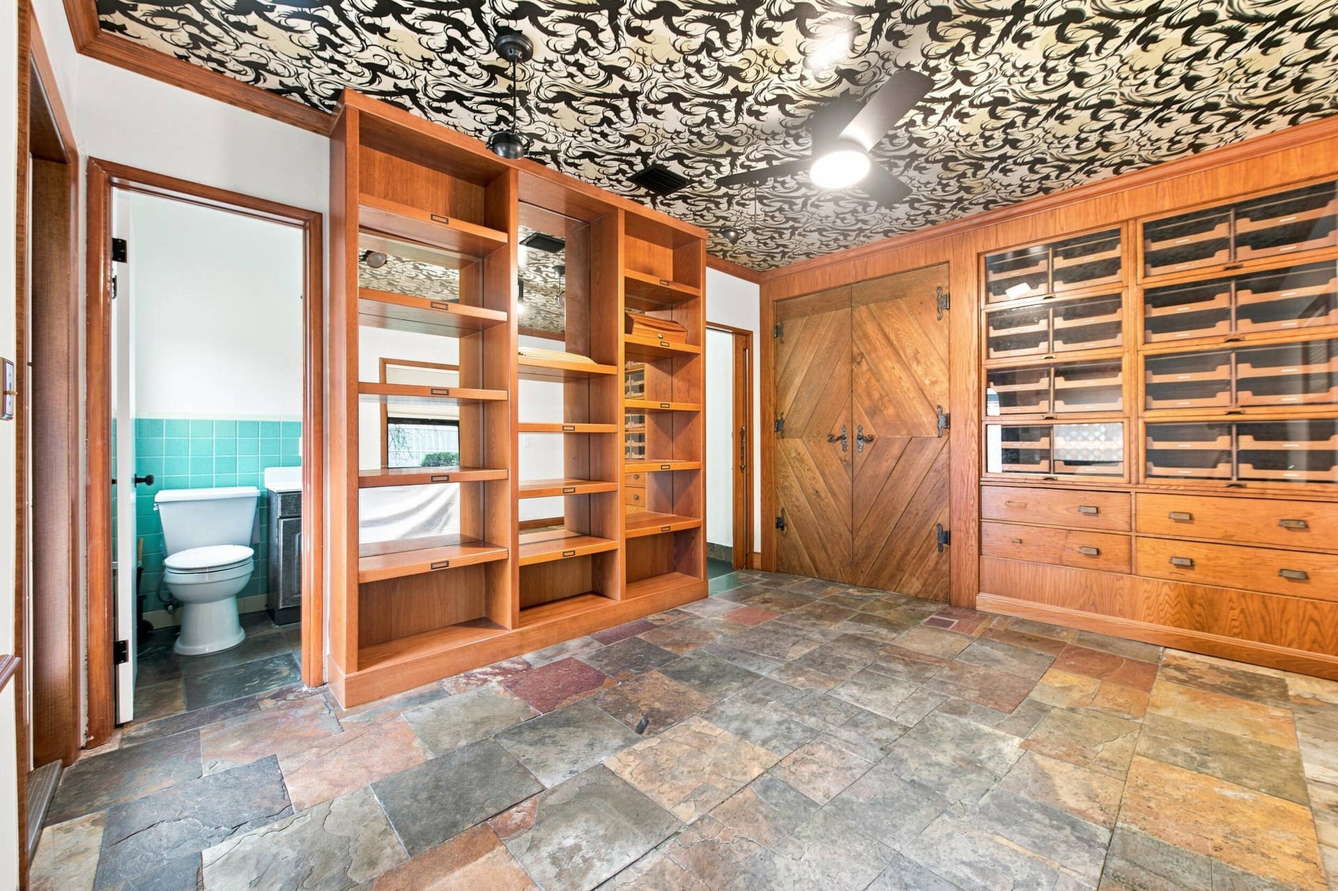 1110 SW 18TH Court, Fort Lauderdale, FL 33315 Custom wood cabinetry with integrated shelving and glass-front storage, patterned ceiling, multi-tonal stone tile flooring, and double doors featuring a diagonal wood plank design