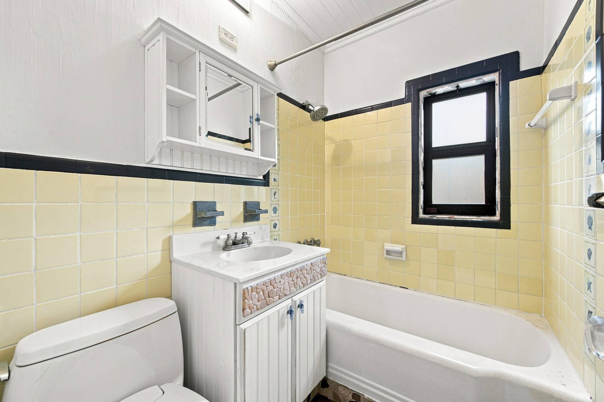 1110 SW 18TH Court, Fort Lauderdale, FL 33315 Bathroom featuring a white vanity with decorative stone inlay, wall-mounted medicine cabinet, bathtub with shower fixture, and yellow ceramic wall tiling with black accent trim