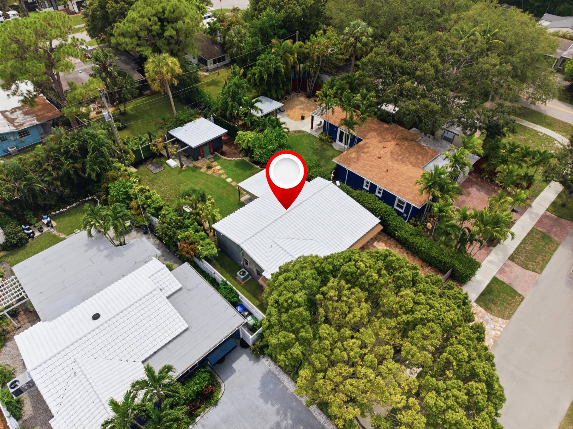 1110 SW 18TH Court, Fort Lauderdale, FL 33315 Aerial perspective of a property featuring a metal roof, landscaped grounds, mature trees, and a detached outbuilding