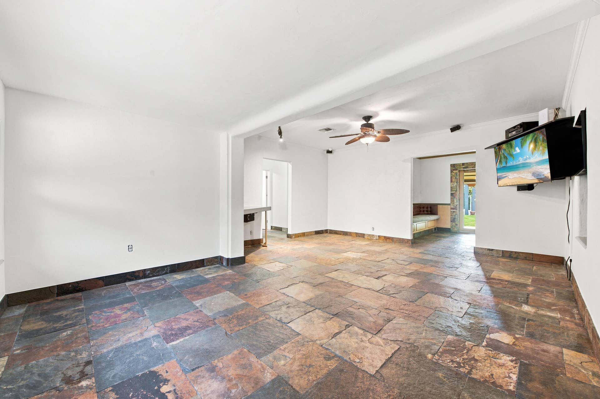 1110 SW 18TH Court, Fort Lauderdale, FL 33315 Interior space featuring multi-tonal natural stone flooring, a central ceiling fan with integrated lighting, built-in recessed wall shelving, and a stone-framed entryway